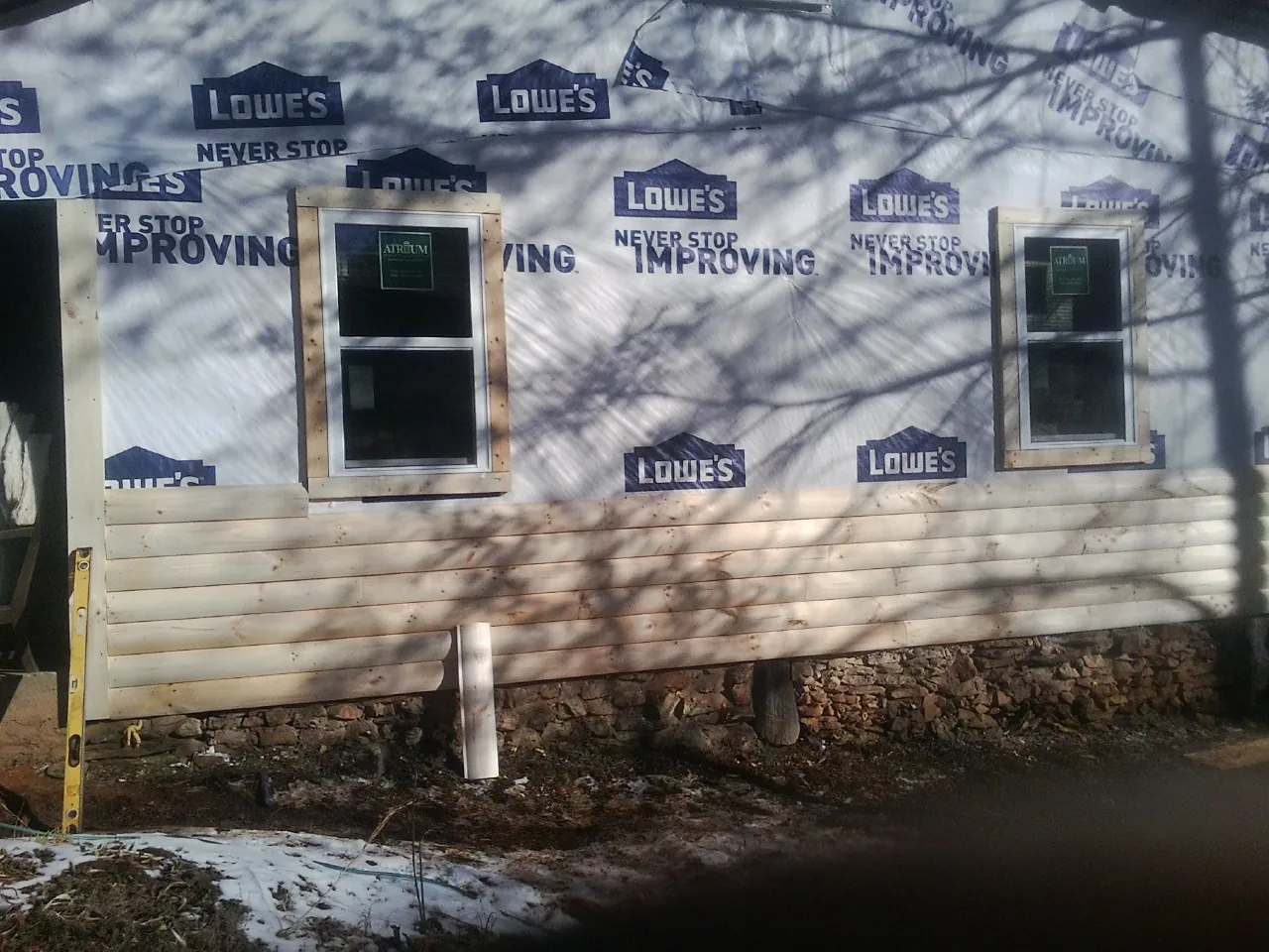 House wrap and new log siding going up on an exterior wall in Farmington