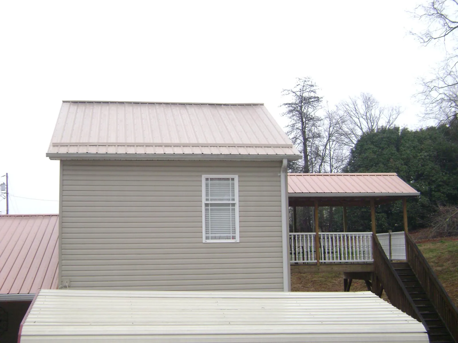 Tan metal roofs on a two story addition and attached porch, from a Roof Replacement job in Farmington